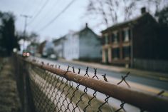 the fence is made of metal and has barbed wire on it, along with houses in the background