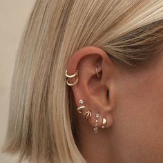 a woman with blonde hair wearing three different ear piercings on her left ear and one in the middle