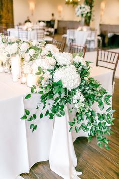 a table with white flowers and candles on it is set up for a wedding reception