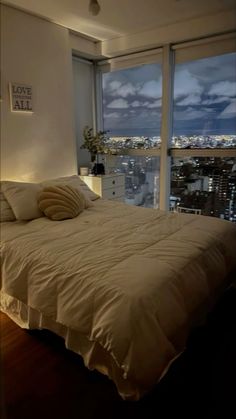 a bedroom with a large window and a bed in front of the cityscape