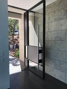 an open door leading into a room with black flooring and stone walls on both sides