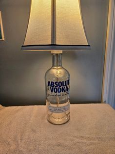 an empty vodka bottle sitting on a bed with a lamp next to it that says absolut vodka