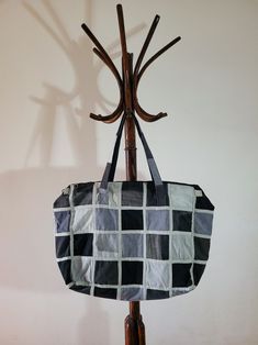 a black and white checkered bag hanging from a coat rack on a wooden pole