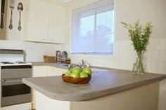 a bowl of green apples sitting on top of a kitchen counter