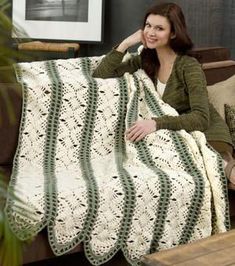 a woman sitting on a couch with a crocheted blanket