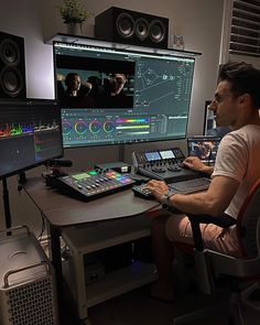 a man sitting at a desk in front of a computer monitor and sound mixing equipment