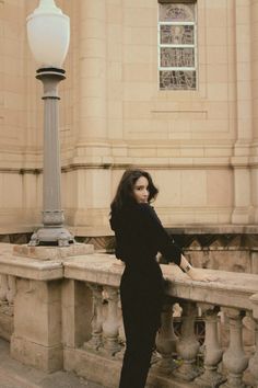 a woman leaning on a ledge next to a street light