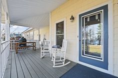 two rocking chairs on the front porch of a house with blue and yellow sidings