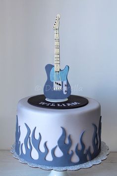 a blue and white cake with a guitar topper on it's bottom tier