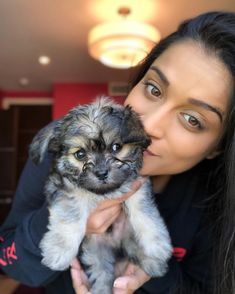 a woman is holding a small dog in her hands while she looks at the camera