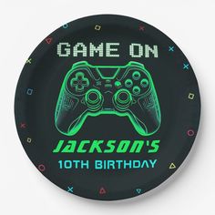 a black plate with a neon green video game controller on it's side that says, game on jackson's 10th birthday