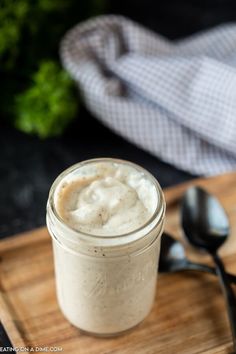 a jar filled with cream sitting on top of a wooden cutting board next to spoons