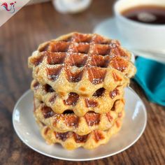 three waffles stacked on top of each other on a plate next to a cup of coffee