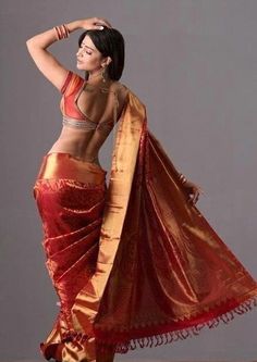 a woman in a red and gold sari dancing with her hands behind her head