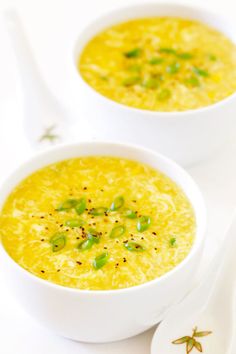 two white bowls filled with soup on top of a table