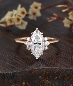 an engagement ring with a pear shaped diamond surrounded by small white diamonds on a wooden surface