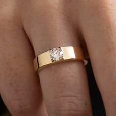 a close up of a person's hand with a gold ring on their finger