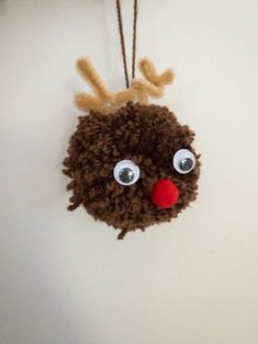 a reindeer ornament hanging on the wall with red nose and brown curly hair