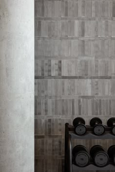 a rack with pots and pans on it in front of a wall made of tiles