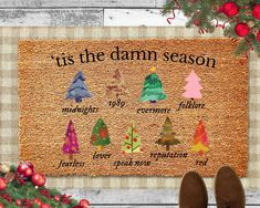 a door mat with christmas trees on it and the words tis the damn season in different languages