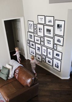 two small children are playing on the floor in front of a wall with black and white pictures