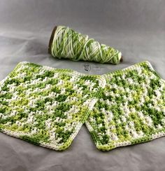 two green and white crocheted coasters next to a spool of yarn