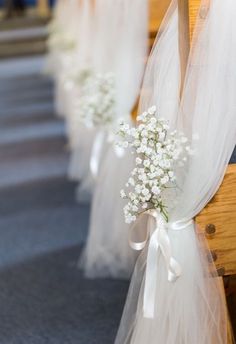 white flowers are tied to the pews at a wedding