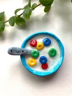 a toy spoon with candy in it sitting on top of a table next to a plant