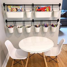 two white chairs and a table in front of a wall with children's toys