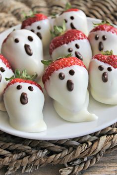 chocolate covered strawberries with white frosting in the shape of ghost faces on a plate