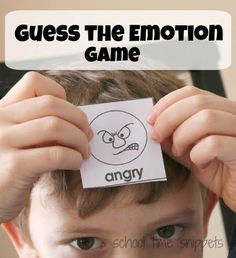 a young boy holding up a piece of paper with the words guess the emotion game on it