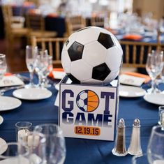 a soccer ball on top of a table with wine glasses and silverware around it