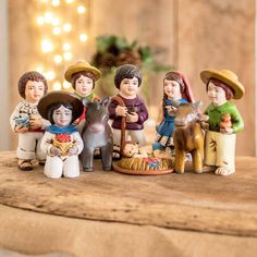 a group of figurines sitting on top of a wooden table next to a christmas tree