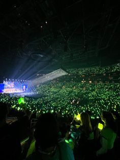 a large crowd at a concert with green lights