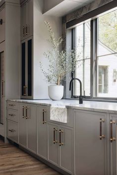 a large kitchen with marble counter tops and gold pulls on the cabinets, along with a white bowl filled with flowers