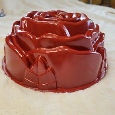 a red cake dish sitting on top of a white bed covered in frosting and icing