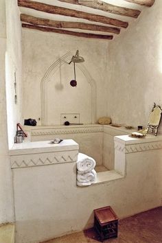 a white bathroom with two sinks and some towels on the shelf in front of it