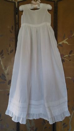 "50s gorgeous white cotton long under dress for a Christening / Baptism. Sleeveless top with two tiny little pearly buttons at the back. Waistband with the long skirt flaring out from it. Bottom of skirt has little tiers of fabric and then a lovely cotton lace trim at the hem. across chest 19\" around, waist 19\" around, skirt length 30\", dress length total 37\"" Solid Dresses With Lace Trim For Daywear, Solid Daywear Dresses With Lace Trim, Solid Color Dresses With Lace Trim For Daywear, Plain White Dresses For Daywear, Fitted Baptism Dress With Lace Trim For Daywear, Fitted Baptism Dress With Lace Trim, Solid Color Summer Baptism Dress, Vintage Cotton Dress For First Communion, Classic Summer First Communion Dress