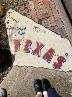 someone is standing on the sidewalk with their feet in front of a sign that says texas