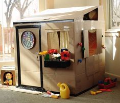 a play house made out of cardboard with toys on the floor