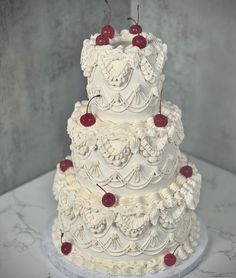 a three tiered wedding cake with cherries on the top is white and red