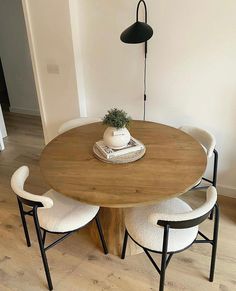 a wooden table with four chairs around it and a potted plant on the top