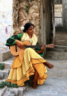 a woman sitting on steps playing a guitar