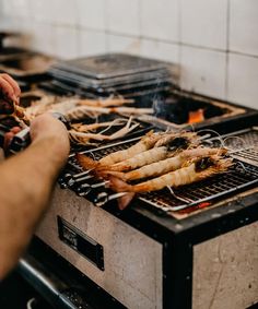 a person cooking food on top of a grill with tongs in their left hand