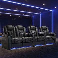 a row of black leather reclining chairs in front of a projector screen with blue lights