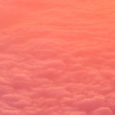 the view from an airplane window shows pink clouds