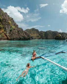 two people are swimming in the ocean near a boat