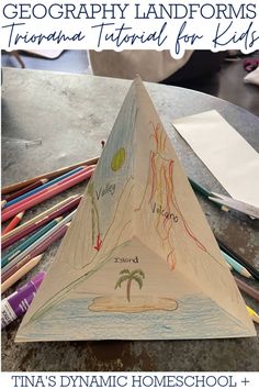 an image of a paper pyramid with writing on it and pencils in the background