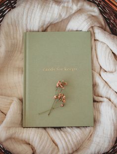 a book sitting on top of a blanket next to a pile of white blankets in a wicker basket