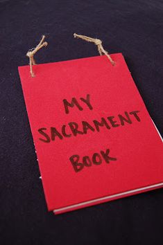 a red book with the words my sacrament book written on it and tied to strings